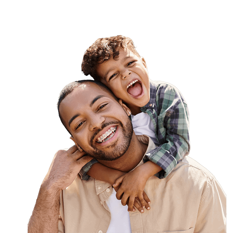 Father and son sharing a playful hug and big smiles outdoors, showing warmth and joy.